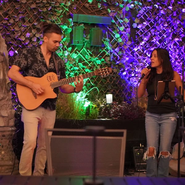 A man playing guitar and a woman singing into a microphone at La Condesa Eatery.