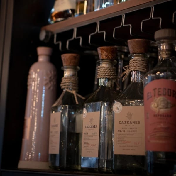 Bottles of Cazcanes Tequila and El Tesoro Reposado on a bar shelf at La Condesa Eatery.