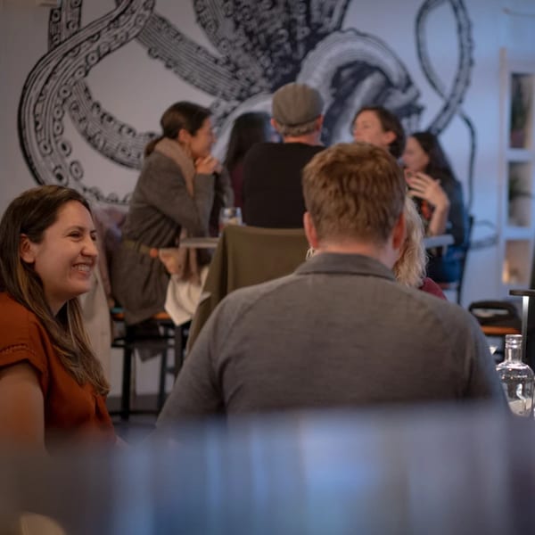 Patrons enjoying conversation at La Condesa Eatery, with an octopus mural in the background.