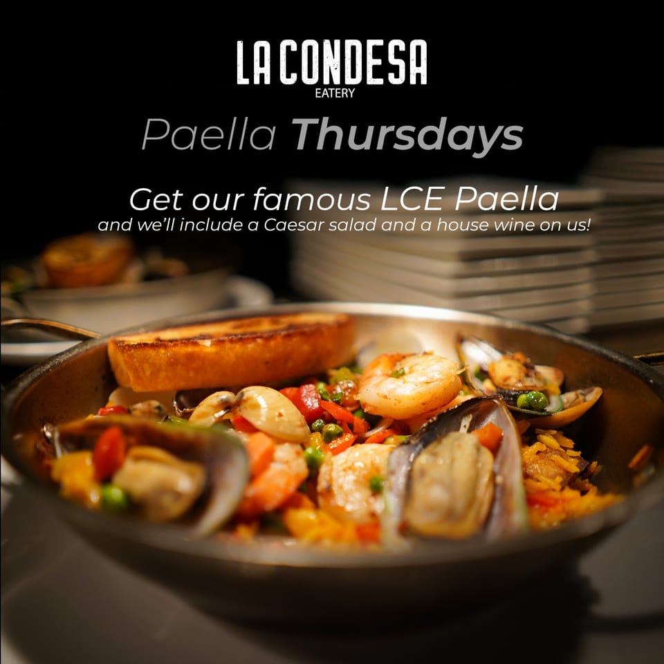 Close-up of a La Condesa Eatery paella with shrimp, mussels, clams, and vegetables, served with toast.