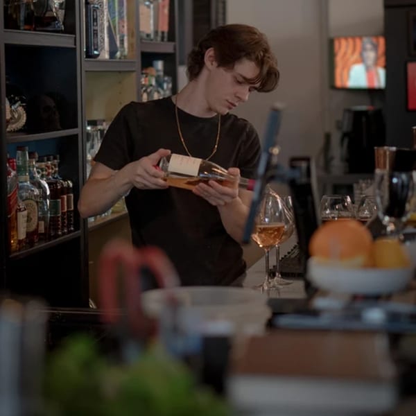 A La Condesa Eatery bartender inspects a bottle of liquor behind the bar.