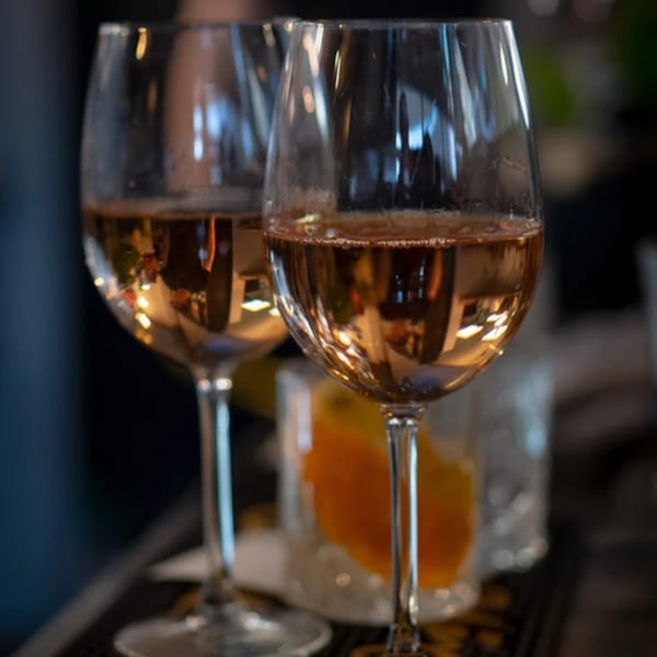 Two wine glasses filled with amber liquid, reflecting warm lights, at La Condesa Eatery.