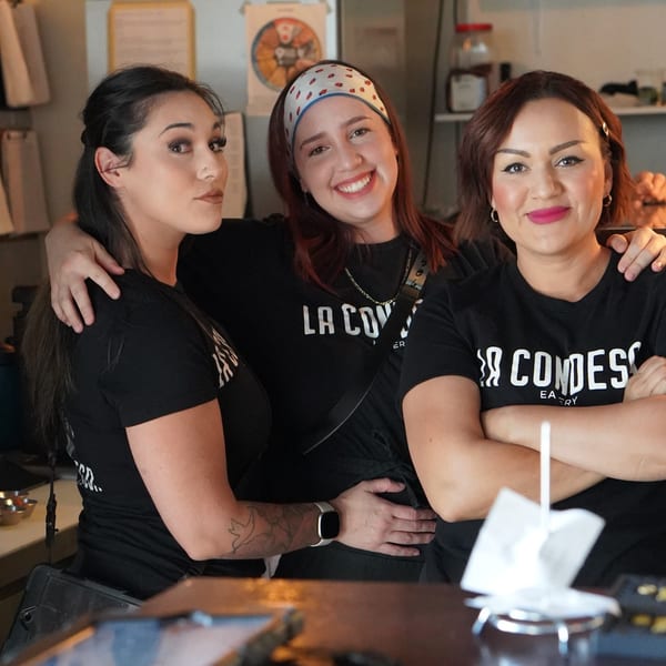 Three smiling La Condesa Eatery staff members in black t-shirts pose together.