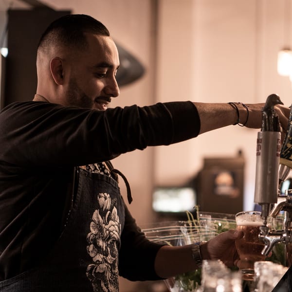 A bartender at La Condesa Eatery pours a beer from a tap into a glass.