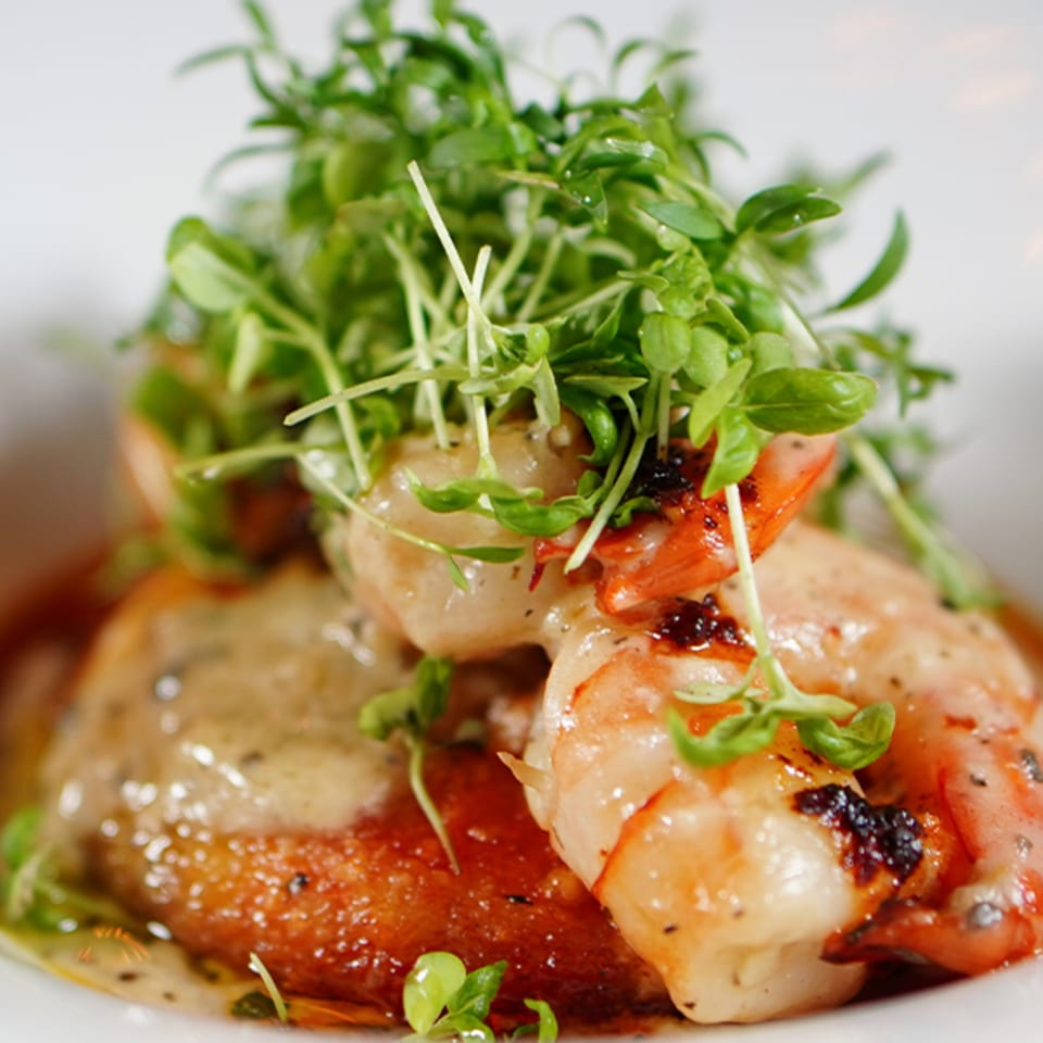 La Condesa Eatery's grilled shrimp dish, garnished with fresh microgreens and a creamy sauce.