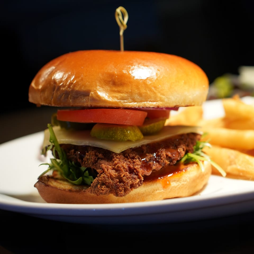 La Condesa Eatery's crispy fried chicken sandwich with cheese, pickles, tomatoes, and fries.