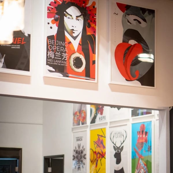 Colorful framed posters, including "Beijing Opera" and abstract art, adorn a white wall at La Condesa Eatery.