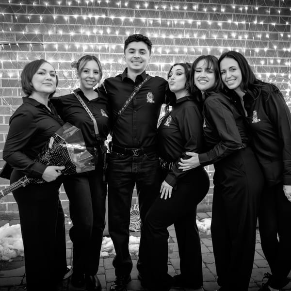 Six La Condesa Eatery staff members in black shirts pose in front of a brick wall with string lights.