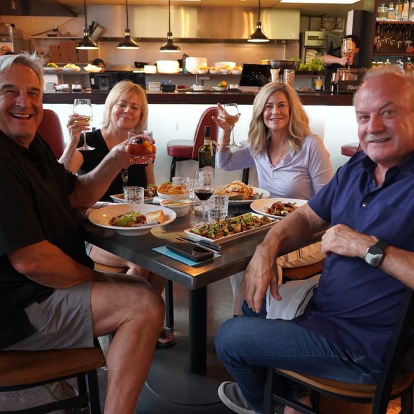 Four happy diners at La Condesa Eatery raising their drinks for a toast.
