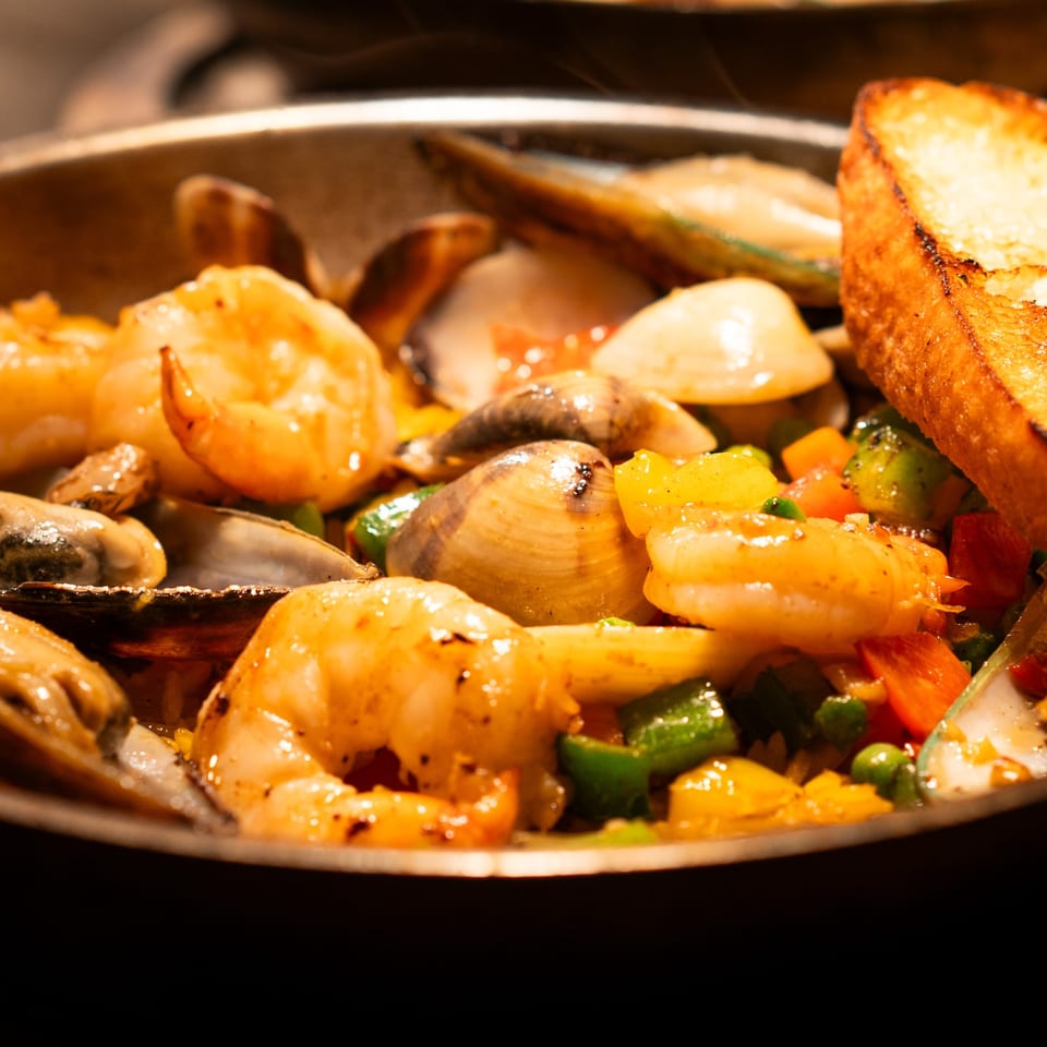 Close-up of La Condesa Eatery's seafood paella with shrimp, mussels, clams, vegetables, and toasted bread.